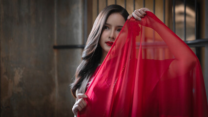Beautiful portrait of an Asian female. A pretty woman wearing a red sash and green loincloth a traditional Thai dress costume. Asian tourists dress to blend in ancient Thai culture.