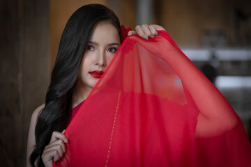 Beautiful portrait of an Asian female. A pretty woman wearing a red sash and green loincloth a traditional Thai dress costume. Asian tourists dress to blend in ancient Thai culture.