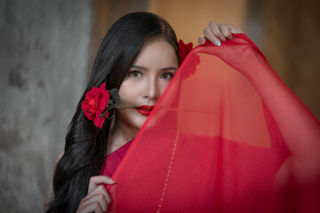 Beautiful portrait of an Asian female. A pretty woman wearing a red sash and green loincloth a traditional Thai dress costume. Asian tourists dress to blend in ancient Thai culture.