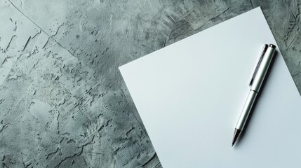 White paper and pen on gray background with space for text top down view of work area