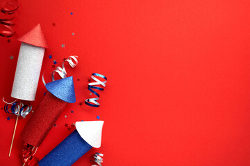 USA flag color fireworks rockets on red background with party streamers and confetti. US national...