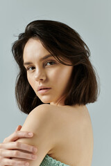 A woman with dark hair and a gentle expression poses against a plain background.