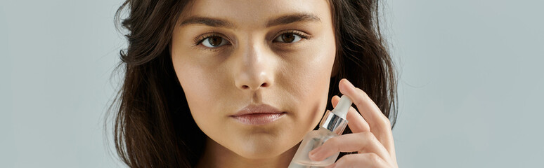 A woman applies a clear serum to her face.