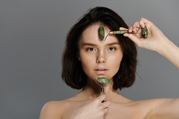 A woman uses a jade roller on her face, a popular beauty treatment.