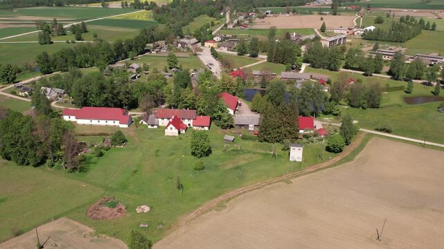 Aerial view of the small town of Malien, located in a green park. The parish is surrounded by well-maintained paths, trees and open grass. Residential buildings and parking