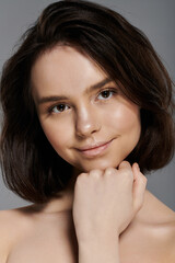 Fototapeta premium A close-up portrait of a woman with dark hair, posing against a simple backdrop.