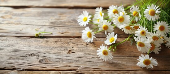 Fototapeta premium View from the top of a wooden table with a bouquet of chamomile flowers, featuring selective focus and a clear background for adding text or other elements - copy space image.