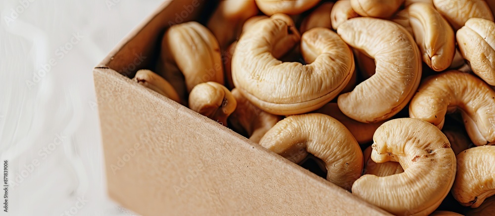 Poster an image showcasing a close-up of a cashew nut in a brown box on a white background, emphasizing the