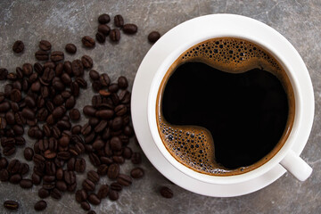 Top view black coffee in a white glass placed on an old cement table with coffee beans.