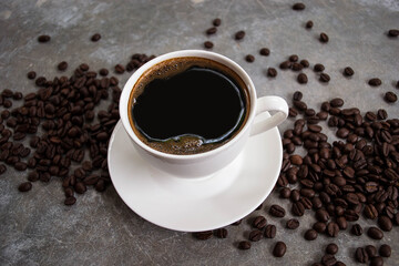 Obraz premium Black coffee in a white glass placed on an old cement table with coffee beans.