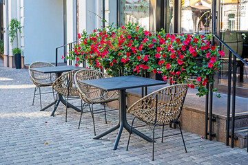 street cafe with wicker furniture and fresh red flowers. Daily Lifestyle.trash in a black trash bag on the street. Everyday waste