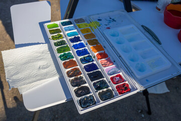 A vibrant watercolor palette on an easel awaits use for plein air painting, reflecting the...