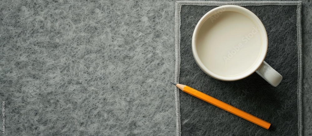 Poster bird's-eye view of a white coffee mug and pencil on a gray felt desk pad with a clear space for imag