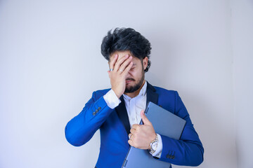 ノートパソコンを持ちながら頭を抱えるビジネスマン