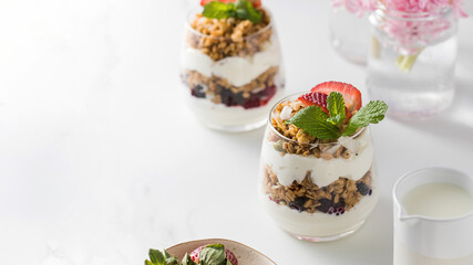 Yogurt with crispy granola, berries and mint leaves for a delicious breakfast. Copy space