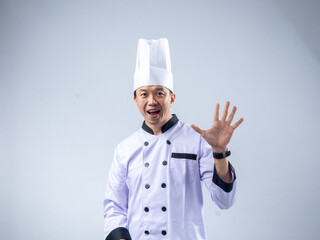 A smiling Asian male chef in a white uniform and hat holds up five fingers, signifying the number five against a light blue background. The setting is professional and engaging