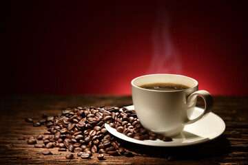 Cup of coffee with smoke and coffee beans on reddish brown background