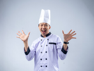 A smiling Asian male chef in a white uniform and hat holds up ten fingers, signifying the number ten, against a light blue background. The setting is professional and engaging