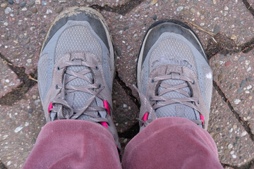 old worn-out shoes, hiking boots on female foot on floor, signs of wear and tear, adding to...