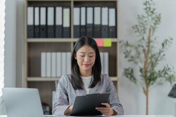 Sharing good business news. Attractive young businesswoman talking on the mobile phone and smiling while sitting at her working place in office and looking at laptop PC.