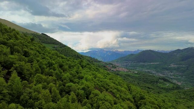 Aerial view of the Alpine mountain peaks on the border of Italy and Switzerland. The drone flies between green slopes and dramatic clouds. Trekking and tourism in the mountains. Green Paneth. Oxygen. 