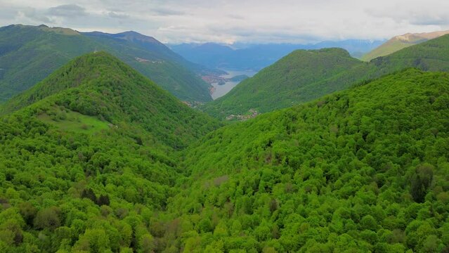 Aerial view of the Alpine mountain peaks on the border of Italy and Switzerland. The drone flies between green slopes and dramatic clouds. Trekking and tourism in the mountains. Green Paneth. Oxygen. 