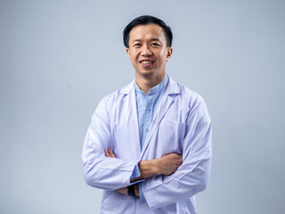 Asian male doctor in a white coat with arms crossed, exuding confidence and professionalism. The...