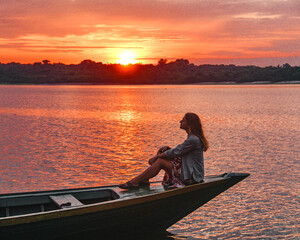 mulher sentada em canoa no pôr do sol no lago acajutuba, em Iranduba, Amazonas 