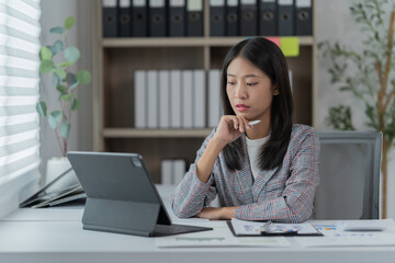 Sharing good business news. Attractive young businesswoman talking on the mobile phone and smiling while sitting at her working place in office and looking at laptop PC.