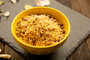 Brazilian manioc flour farofa with bacon in a yellow bowl