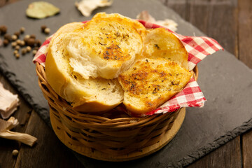 Bread toast slices with oregano and butter inside a wooden basket in warm colors