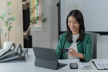 mage of a young Asian businesswoman holding a credit card.