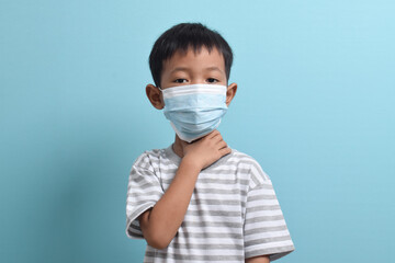 Asian Boy wearing health mask isolated on blue background. Medical and health concept. Human population viruses, infections, flu disease prevention