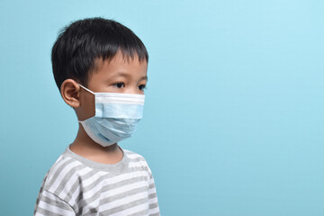 Asian Boy wearing health mask isolated on blue background. Medical and health concept. Human population viruses, infections, flu disease prevention