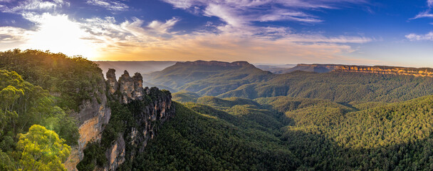 A panoramic view of the Three Sisters rock formation in the Blue Mountains, Australia. The photo was taken from the scenic Echo Point Lookout overlooking the vast mountain landscape.