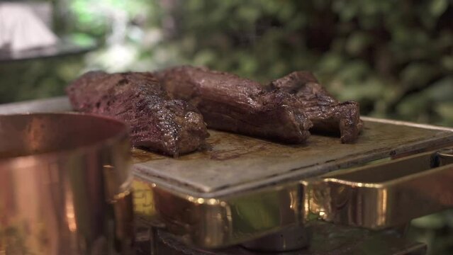 cortes de carne servidos sobre una tabla de piedra en una fiesta