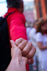 Go to festival San Fermin, Pamplona, Spain. Male and female hands over San Fermin street crowd. Man leads her woman in traditional spanish show. Fiesta, encierro, corrida concept.