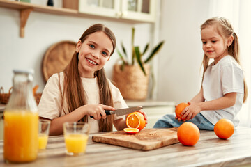 A group of children happily drinking fresh orange juice in a vibrant, contemporary kitchen