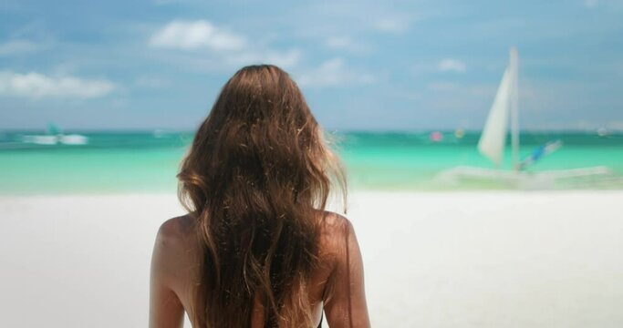 Attractive young woman in bikini relax sandy shore of Boracay Islands White Beach, enjoying the sun and sea on a clear day, blue sky. Female tourist on summer vacation. Lifestyle holiday concept