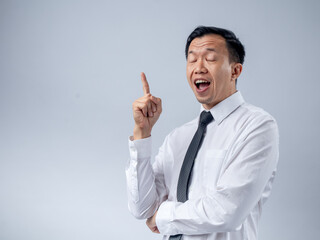 Asian businessman in a white shirt and black tie raising his index finger as if sharing an idea, looking up with an excited expression against a plain light background. The image conveys innovation