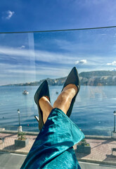 Woman's legs in high heel shoes on the background of the sea at the resort