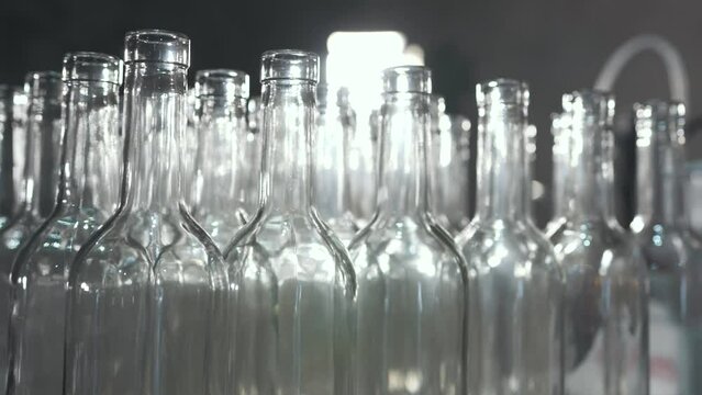 Many empty glass transparent clean sterile bottles in the factory for filling alcoholic or non-alcoholic beverages. One of the stages of wine production