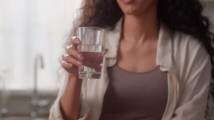 Hispanic Caucasian woman girl female happy drinking glass of still mineral water refresh organic beverage drink at kitchen enjoy smiling diet aqua balance delivery nutrition health wink eye smile - Powered by Adobe