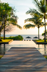 View from the wooden deck of the infinity pool on the beach, ocean and tall palm trees.