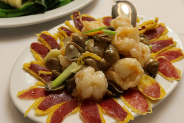 close up of traditional Cantonese Hong Kong style restaurant dish- shrimp, mushroom, dry ham and onion on a white plate