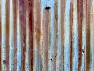 A rusty metal shed wall, with its weathered surface and rich patina, exudes rugged industrial charm, telling a story of time and resilience in a rustic, picturesque setting.