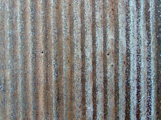 A rusty metal shed wall displays weathered texture and rich patina, embodying industrial decay and rugged beauty, with its corroded surface telling a story of time and resilience.