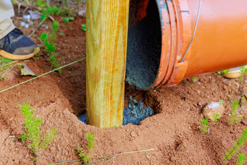 Concrete pouring of newly installed timber fencing wooden fence posts