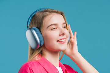 Naklejka premium Cute woman listening streaming music, enjoying dance with headphones on blue