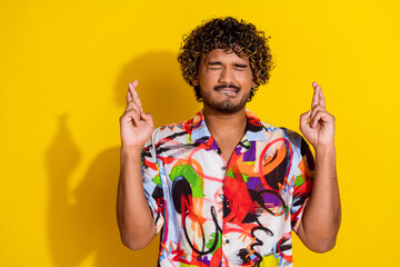 Portrait of nice young man bite lips crossed fingers wear shirt isolated on yellow color background